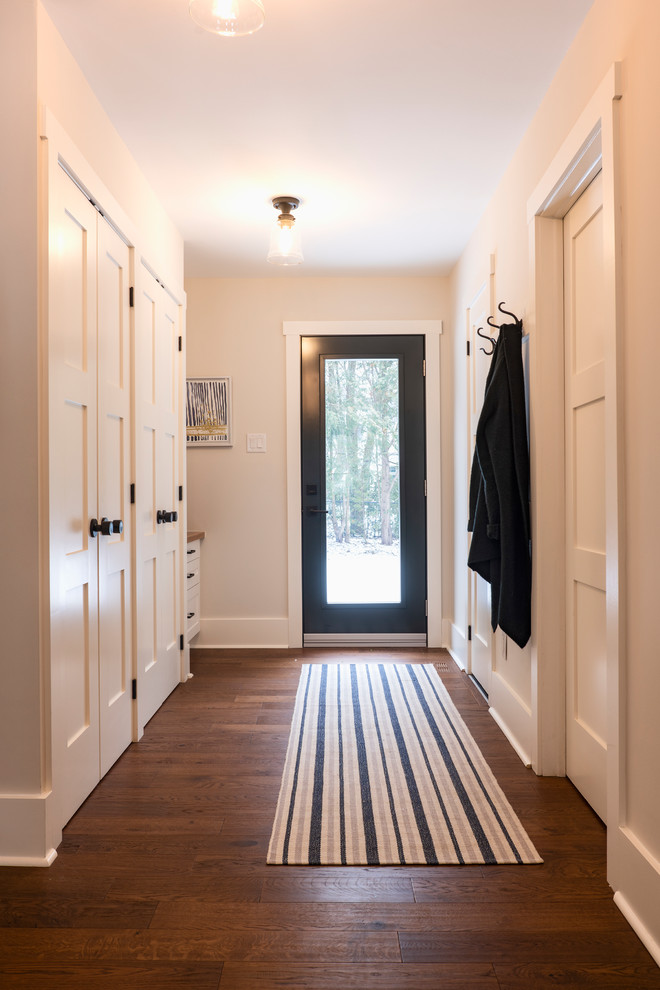 Imagen de hall campestre de tamaño medio con paredes beige, suelo de madera en tonos medios, puerta simple, puerta negra y suelo marrón