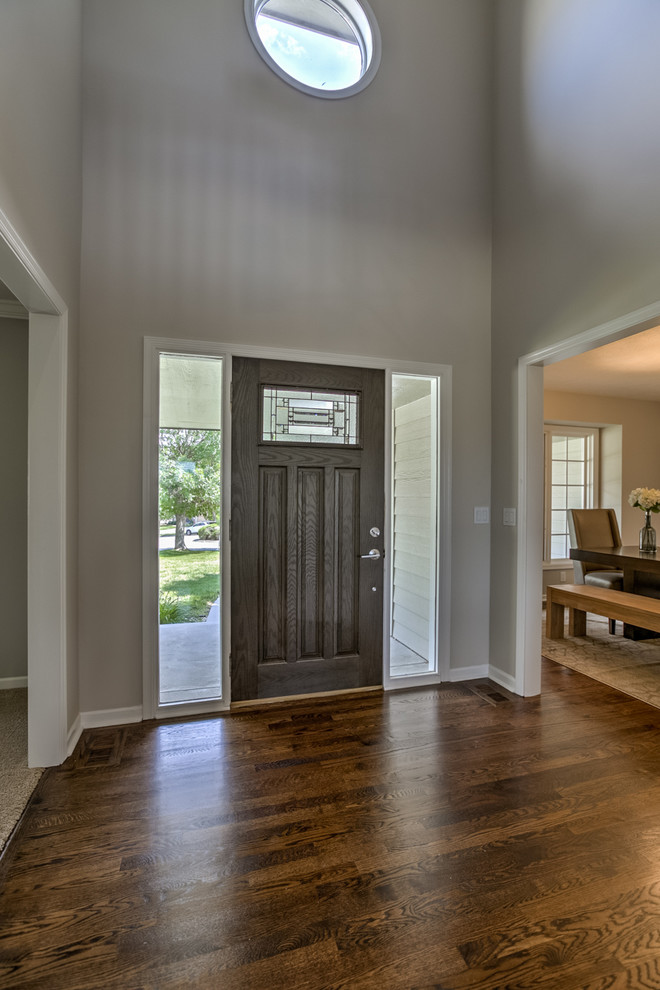 Diseño de entrada minimalista con paredes grises, suelo de madera en tonos medios, puerta simple y puerta de madera oscura