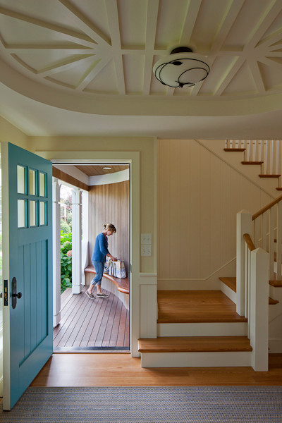 Immagine di una porta d'ingresso stile marinaro di medie dimensioni con pareti beige, pavimento in legno massello medio, una porta singola, una porta blu e pavimento marrone