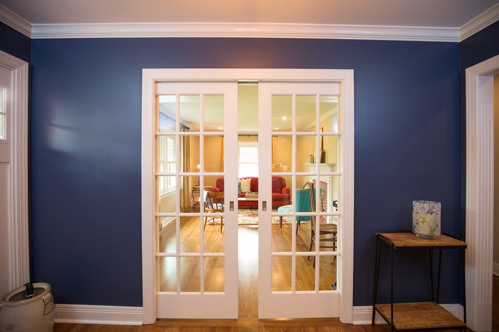 Aménagement d'un hall d'entrée éclectique avec un mur bleu, un sol en bois brun, une porte simple et une porte blanche.