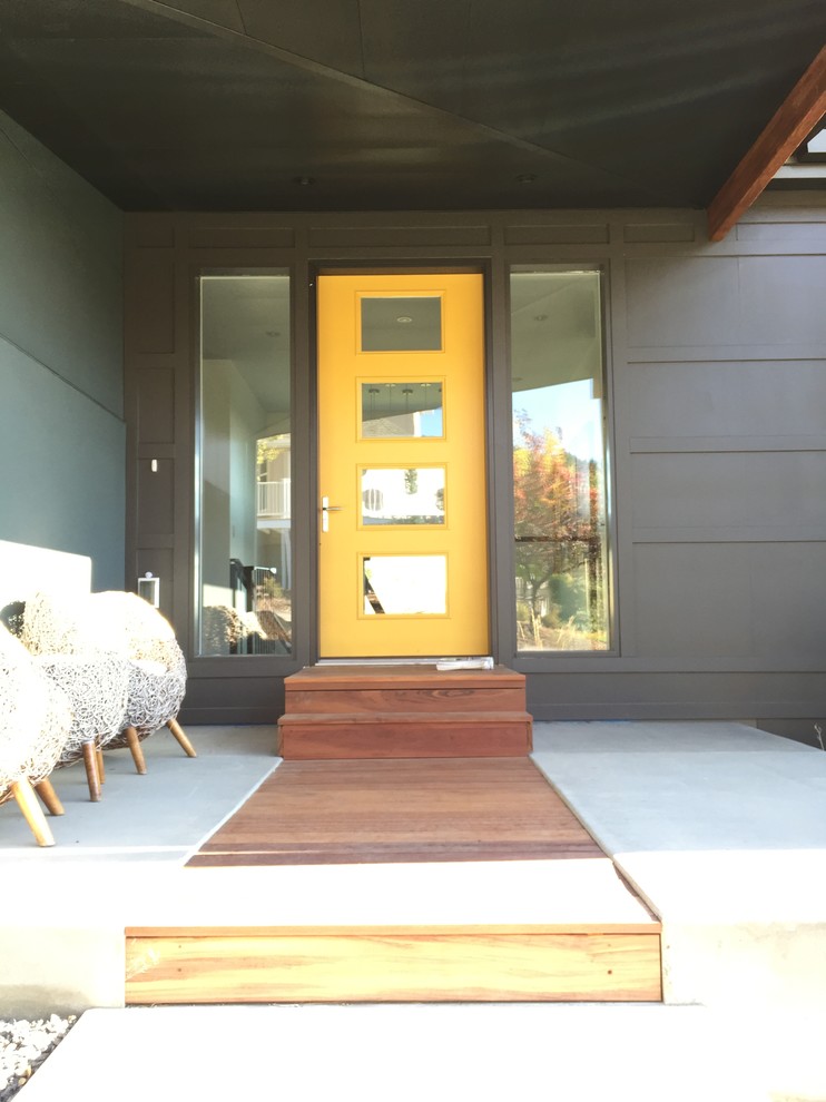 Cette photo montre une porte d'entrée moderne de taille moyenne avec un mur vert, sol en béton ciré, une porte simple et une porte jaune.