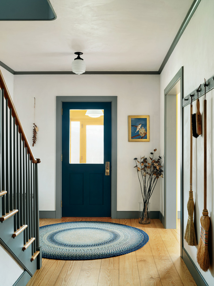 Example of a farmhouse light wood floor entryway design in New York with white walls and a glass front door