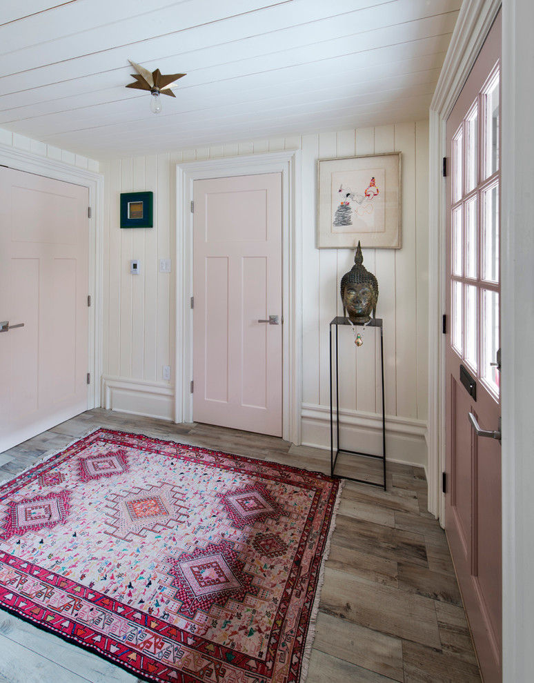 Modelo de entrada campestre con paredes blancas, suelo de madera en tonos medios y puerta simple