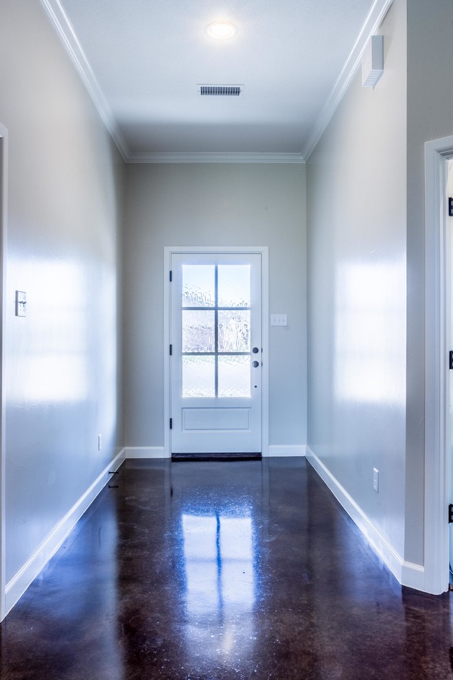 Aménagement d'une grande porte d'entrée contemporaine avec un mur gris, une porte simple, une porte blanche, un sol marron et sol en béton ciré.