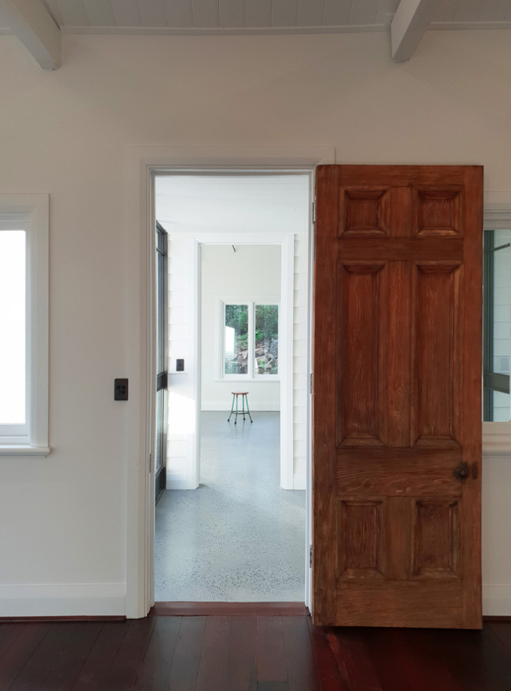 Idée de décoration pour une entrée tradition de taille moyenne avec un couloir, un mur blanc, sol en béton ciré, une porte simple, une porte en bois brun, un sol gris et un plafond en lambris de bois.