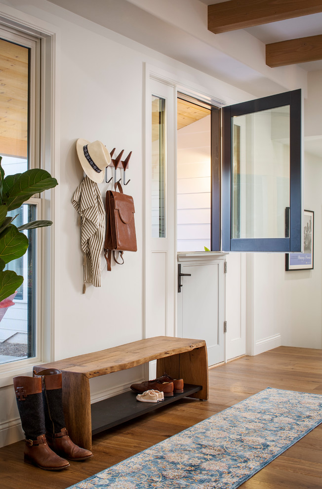 サンフランシスコにあるラグジュアリーな広いトランジショナルスタイルのおしゃれな玄関 (白い壁、無垢フローリング、黒いドア、茶色い床) の写真