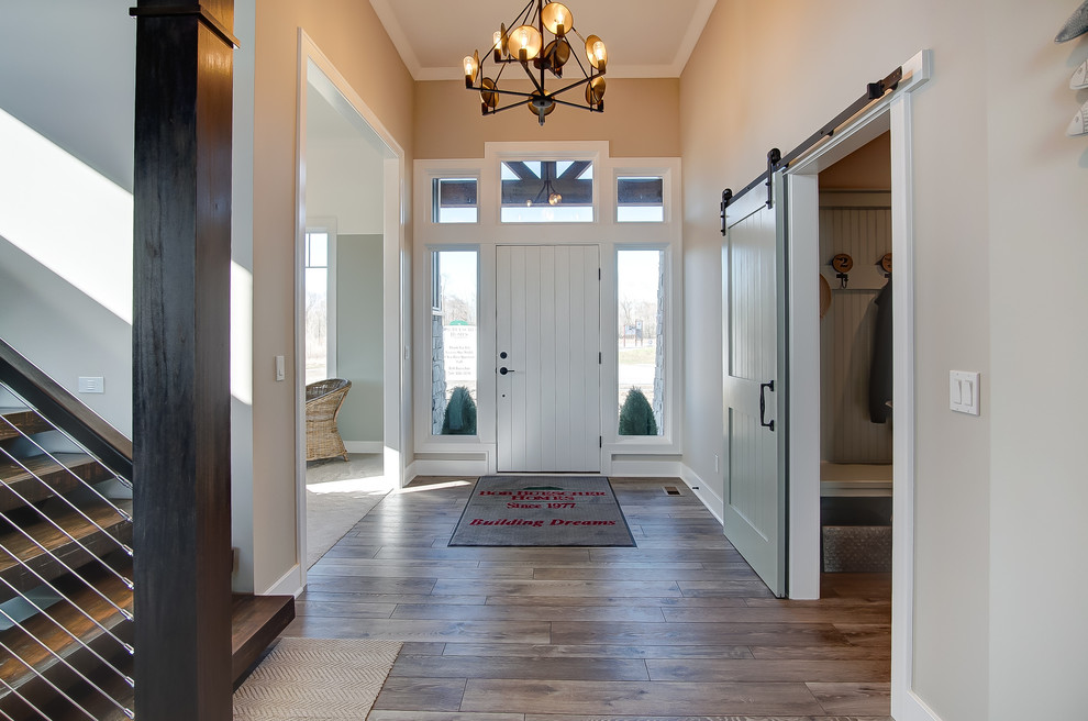 他の地域にあるラグジュアリーな広いトランジショナルスタイルのおしゃれな玄関ロビー (ベージュの壁、クッションフロア、白いドア、茶色い床) の写真