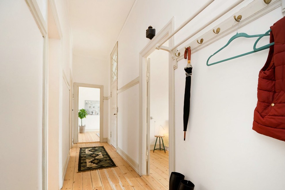 Example of a mid-sized danish light wood floor entryway design in Other with white walls
