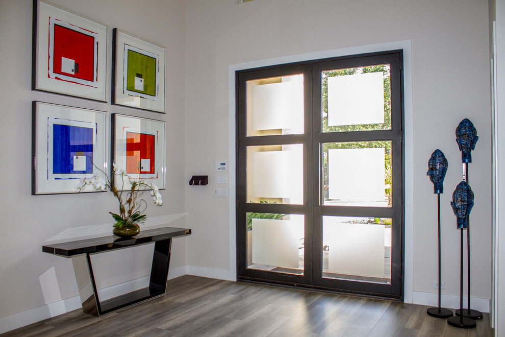 Cette image montre une grande porte d'entrée design avec un mur beige, parquet foncé, une porte double et une porte en verre.
