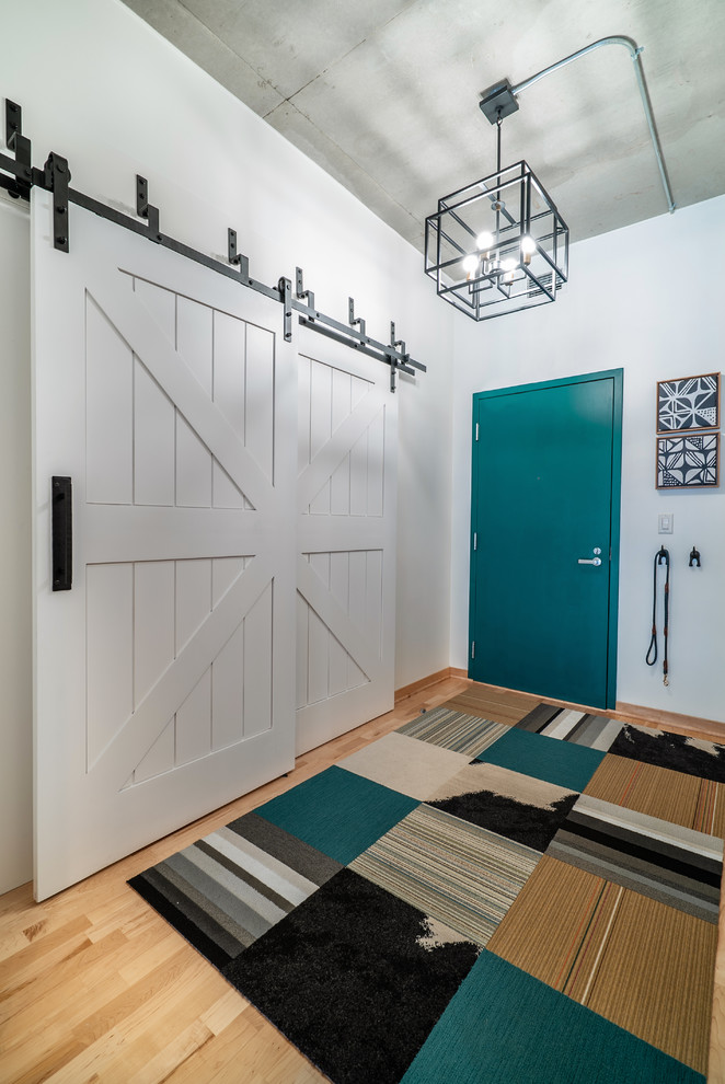 Aménagement d'une porte d'entrée industrielle de taille moyenne avec un mur blanc, parquet clair, une porte simple, une porte bleue et un sol marron.