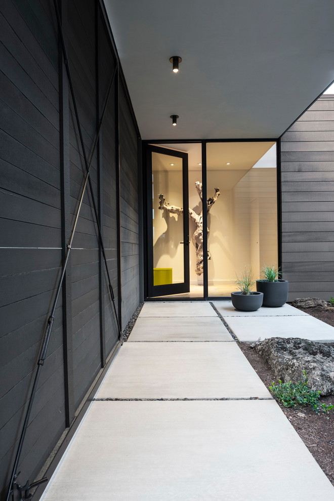 Ispirazione per un ingresso o corridoio minimalista di medie dimensioni con pavimento in cemento, una porta singola e una porta in vetro