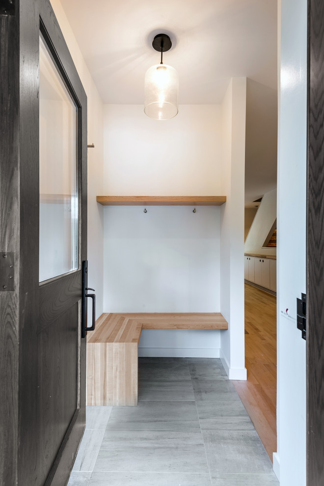 Idée de décoration pour un hall d'entrée minimaliste avec un mur blanc, un sol en carrelage de céramique, une porte simple, une porte en bois foncé et un sol gris.