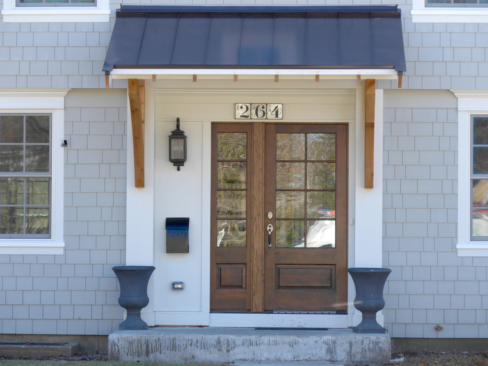 Imagen de puerta principal clásica de tamaño medio con paredes grises, suelo de cemento, puerta simple, puerta marrón y suelo gris