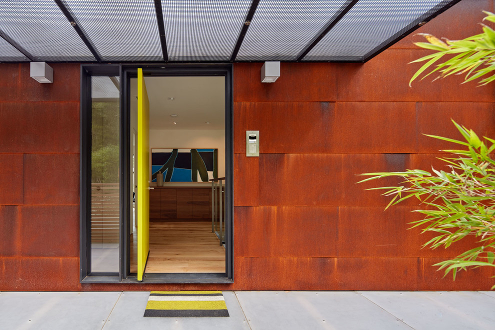 Inspiration pour une grande porte d'entrée minimaliste avec un mur marron, un sol en bois brun, une porte pivot et une porte verte.