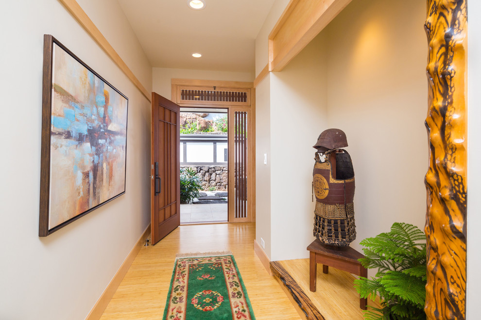 Mittelgroßer Asiatischer Eingang mit Korridor, weißer Wandfarbe, hellem Holzboden, Einzeltür und hellbrauner Holzhaustür in Hawaii
