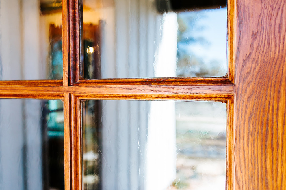 オースティンにある高級な広いカントリー風のおしゃれな玄関ドア (茶色い壁、竹フローリング、ガラスドア、茶色い床) の写真