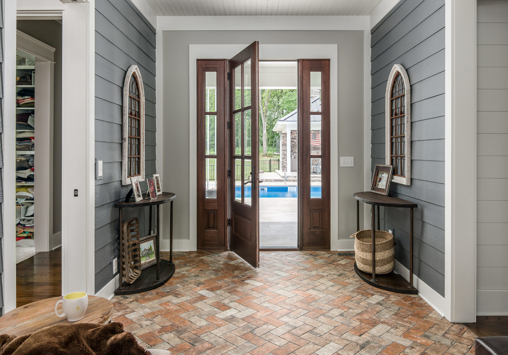 Diseño de vestíbulo tradicional renovado con paredes grises, suelo de ladrillo, puerta simple y puerta de madera en tonos medios
