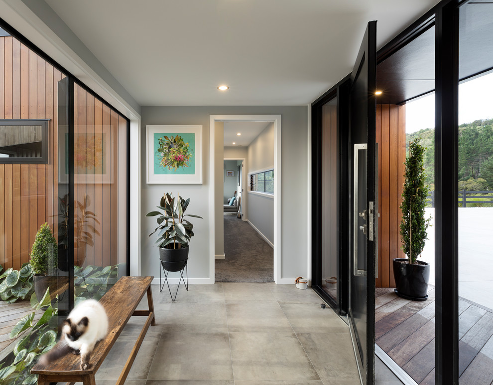 Стильный дизайн: узкая прихожая в современном стиле с серыми стенами, одностворчатой входной дверью, черной входной дверью и серым полом - последний тренд