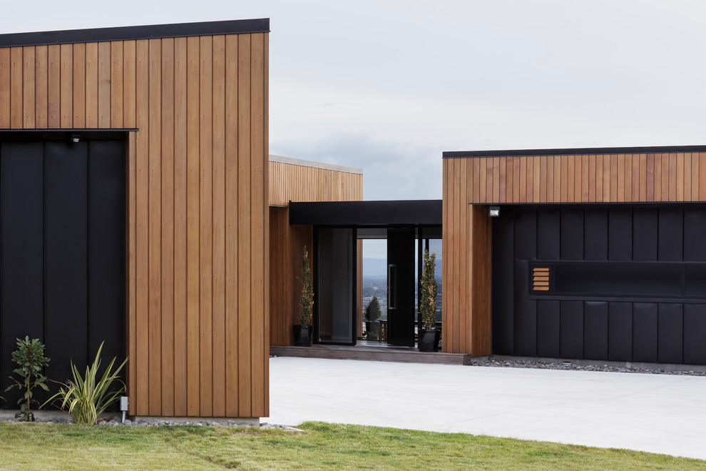 Idée de décoration pour une porte d'entrée design avec un mur marron, sol en béton ciré, une porte simple, une porte noire et un sol gris.