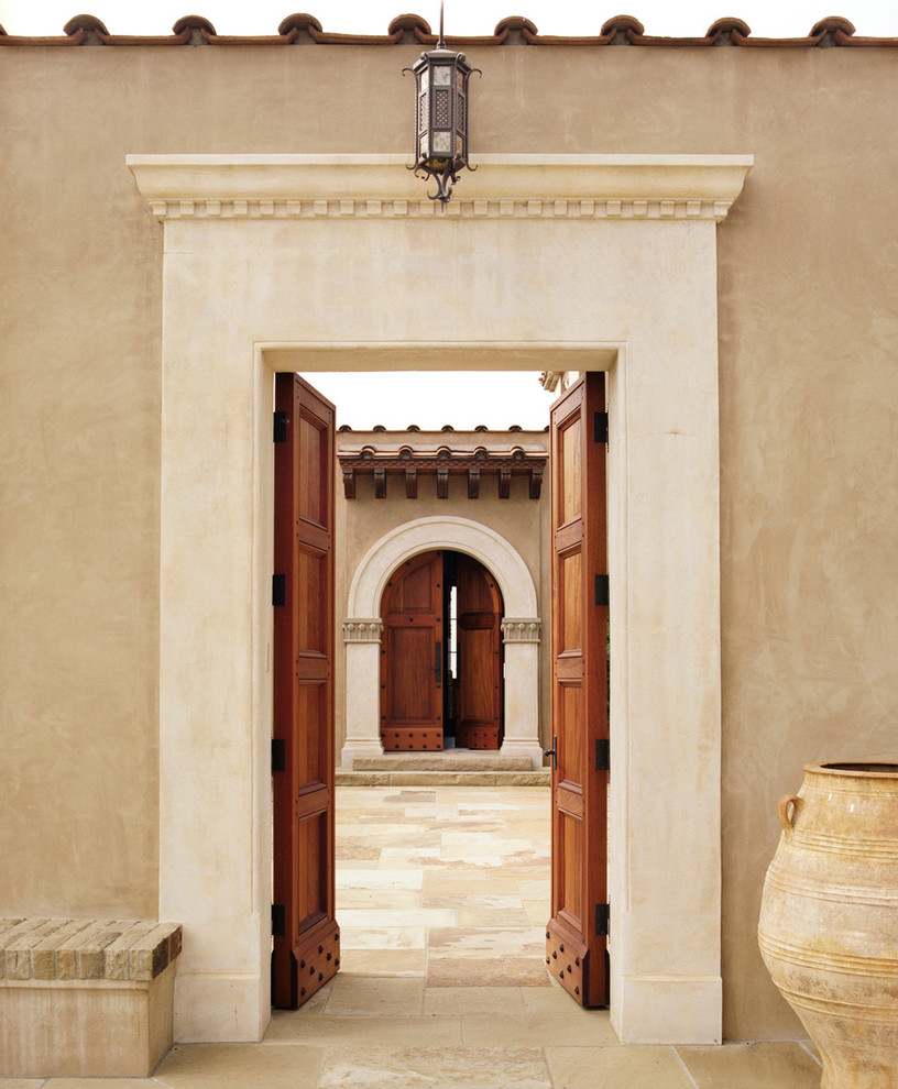 На фото: входная дверь в средиземноморском стиле с бежевыми стенами и двустворчатой входной дверью