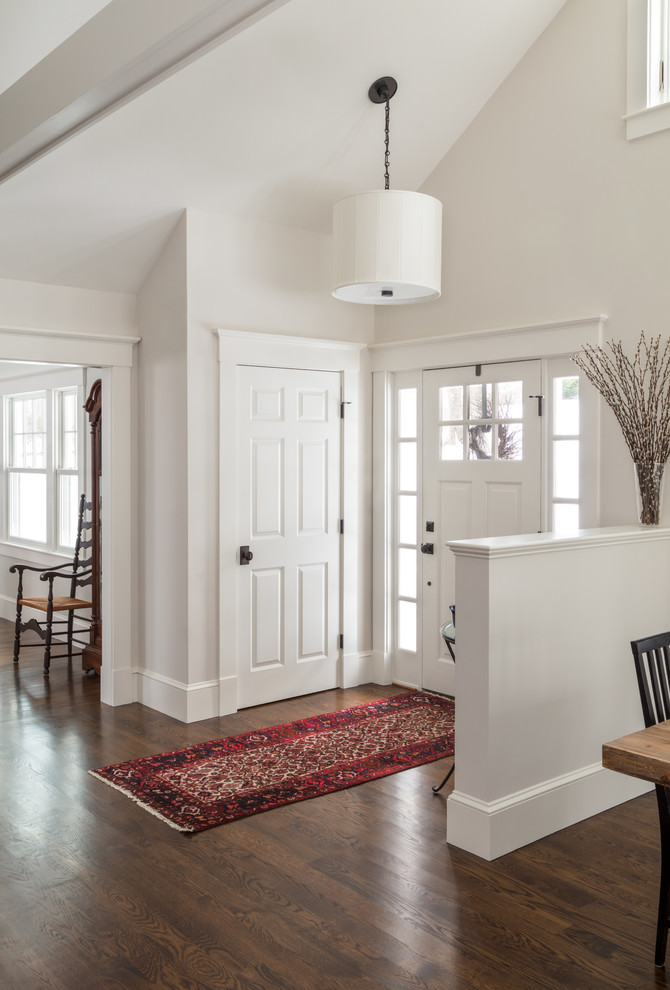 Exempel på en klassisk ingång och ytterdörr, med vita väggar, mörkt trägolv, en enkeldörr, en vit dörr och brunt golv