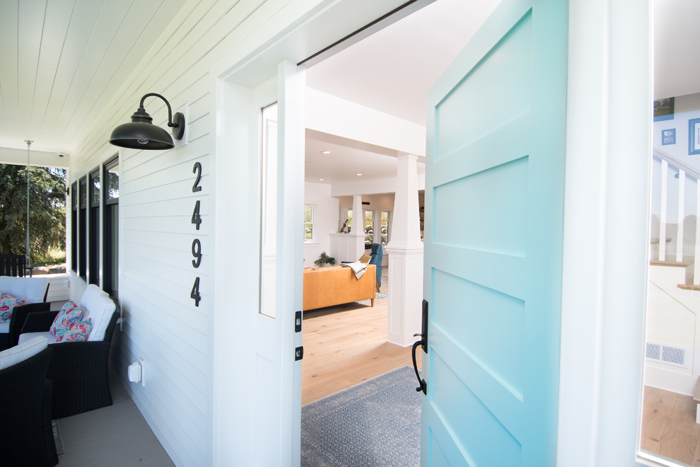 Imagen de puerta principal de estilo de casa de campo grande con paredes blancas, suelo de madera en tonos medios, puerta simple y puerta azul