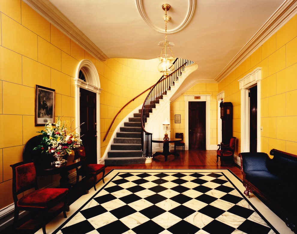 ニューヨークにあるヴィクトリアン調のおしゃれな玄関ホール (黄色い壁、大理石の床) の写真