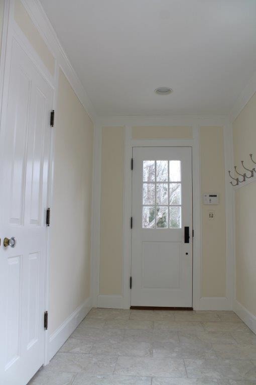 Klassisk inredning av ett kapprum, med beige väggar, klinkergolv i porslin, en enkeldörr och en vit dörr