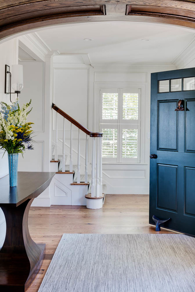 Aménagement d'une porte d'entrée bord de mer de taille moyenne avec un mur blanc, parquet clair, une porte simple et une porte bleue.