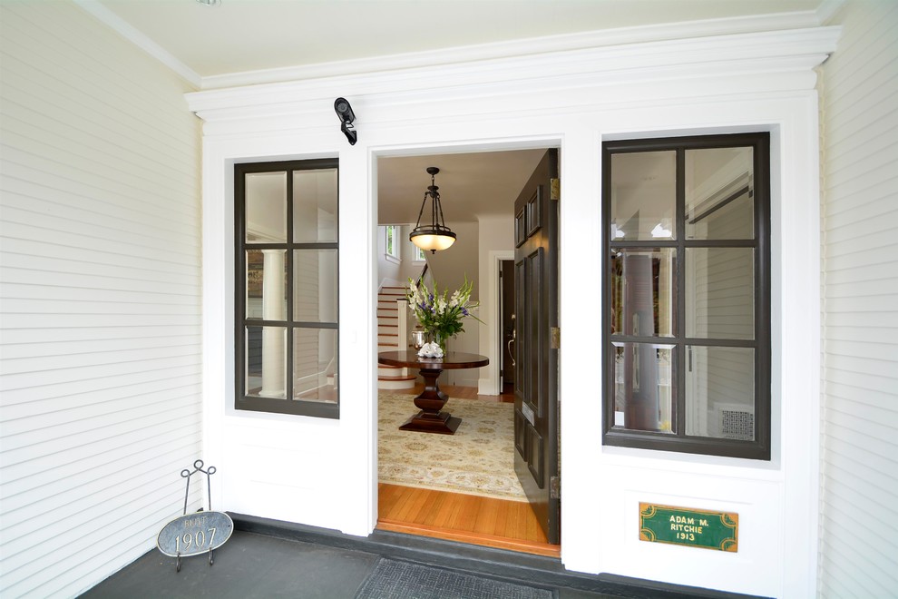 Aménagement d'une porte d'entrée rétro de taille moyenne avec un mur blanc, un sol en bois brun, une porte simple, une porte marron et un sol gris.