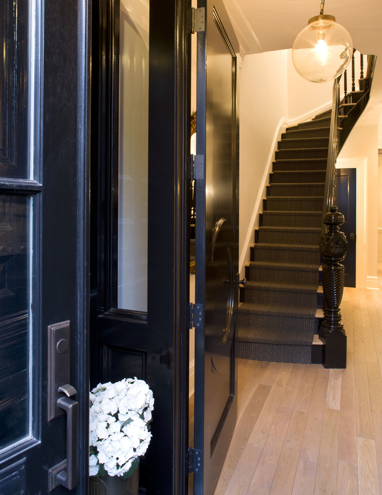 ニューアークにあるトランジショナルスタイルのおしゃれな玄関ラウンジ (淡色無垢フローリング、黒いドア) の写真
