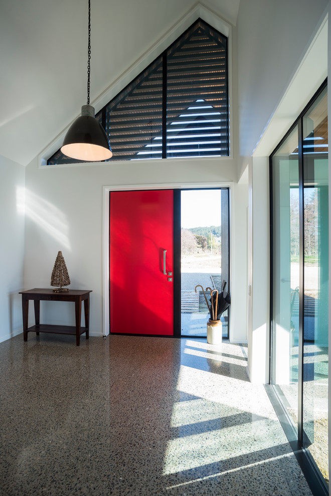 Пример оригинального дизайна: входная дверь среднего размера с белыми стенами, бетонным полом, одностворчатой входной дверью и красной входной дверью