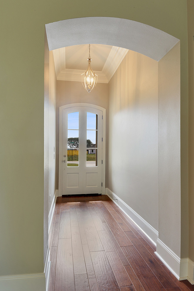 Inspiration for a timeless medium tone wood floor entryway remodel in New Orleans with beige walls and a white front door