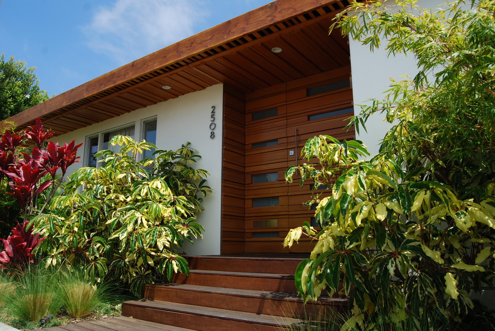 Retro Haustür mit weißer Wandfarbe, braunem Holzboden, Drehtür, hellbrauner Holzhaustür und braunem Boden in Los Angeles