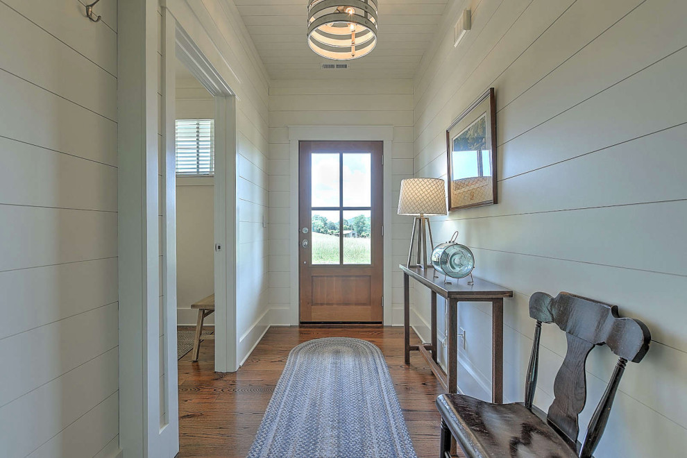 Kleines Rustikales Foyer mit weißer Wandfarbe, braunem Holzboden, Drehtür, hellbrauner Holzhaustür, Holzdielendecke und Holzdielenwänden in Sonstige