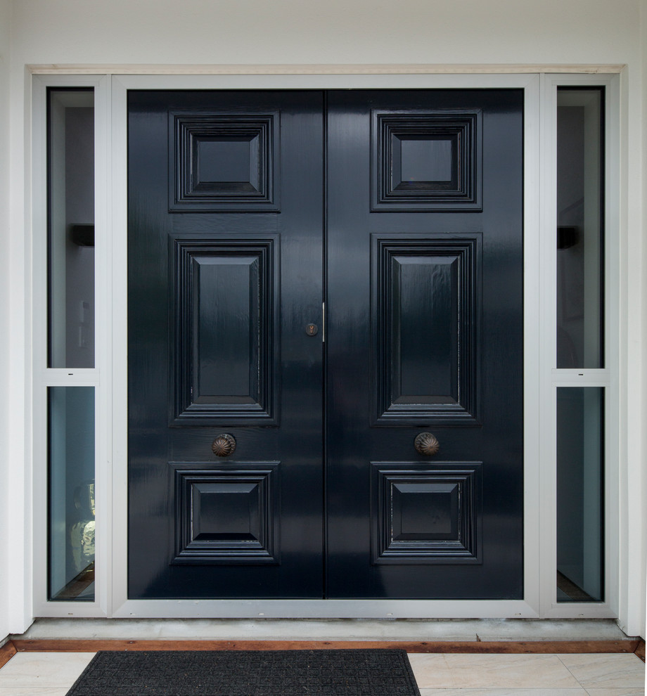 Cette image montre une porte d'entrée traditionnelle de taille moyenne avec une porte double et une porte grise.