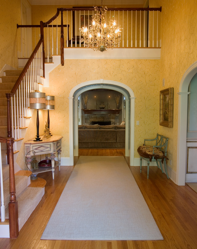 Inspiration pour un hall d'entrée traditionnel de taille moyenne avec un mur jaune et un sol en bois brun.