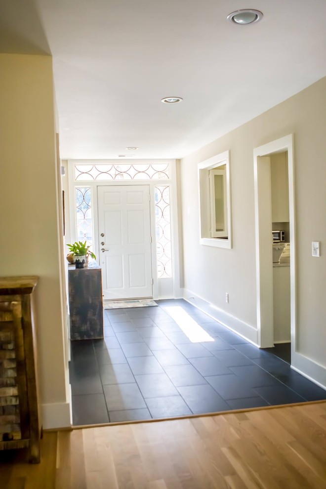 This is an example of a medium sized classic front door in Orange County with beige walls, slate flooring, a single front door, a white front door and black floors.