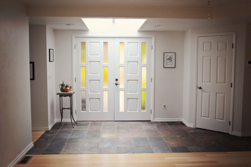 Idee per una piccola porta d'ingresso etnica con pareti bianche, pavimento in ardesia, una porta a due ante, una porta bianca e pavimento multicolore