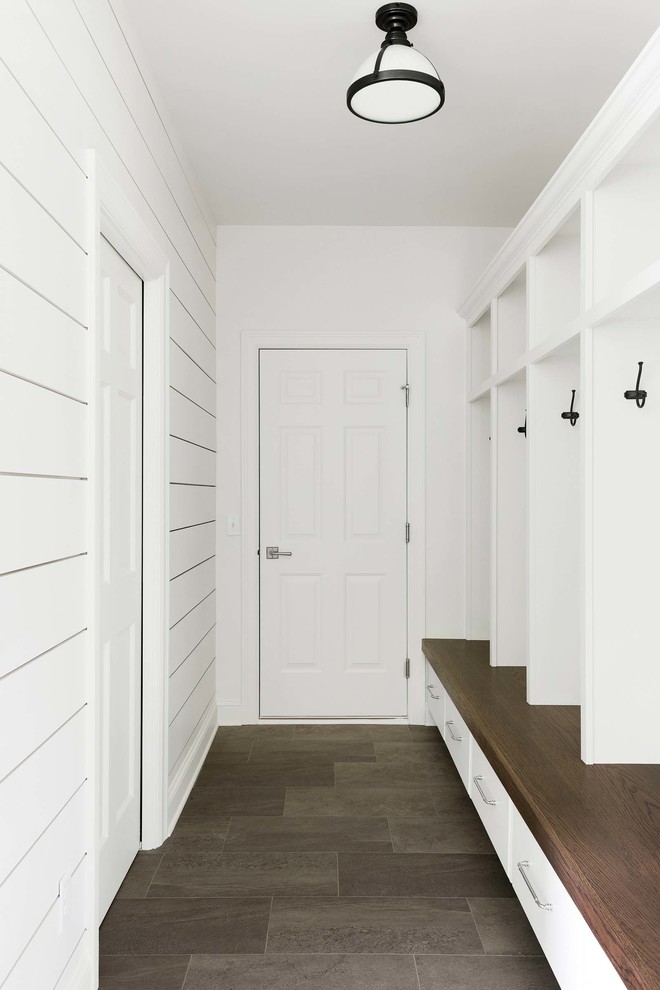 Exempel på ett mellanstort kapprum, med vita väggar och grått golv