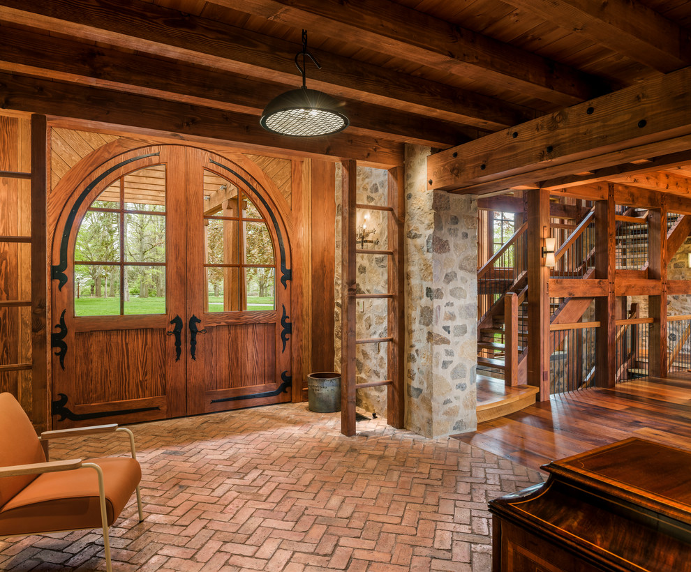 Idée de décoration pour un hall d'entrée champêtre avec un sol en brique, une porte double et une porte en bois brun.