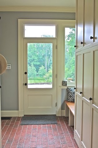 На фото: тамбур в стиле неоклассика (современная классика) с серыми стенами, кирпичным полом, одностворчатой входной дверью и белой входной дверью с