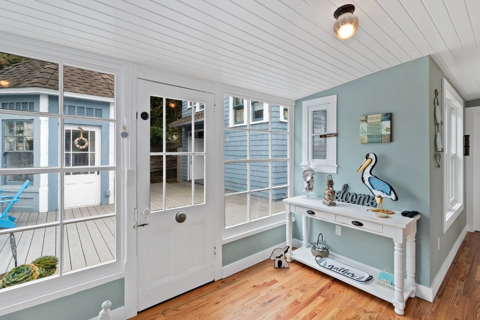 Maritim inredning av en liten entré, med mellanmörkt trägolv, brunt golv, blå väggar, en enkeldörr och en vit dörr