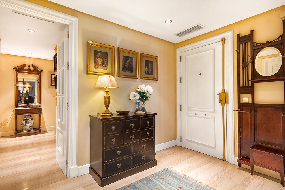 Aménagement d'une petite porte d'entrée classique avec un mur jaune, un sol en carrelage de céramique, une porte simple et une porte blanche.