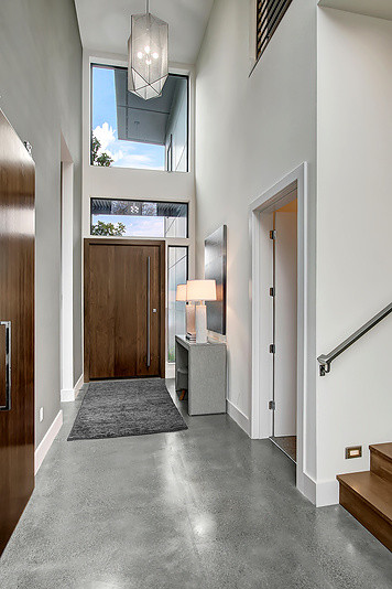 Foto di un ingresso minimalista di medie dimensioni con pareti bianche, pavimento in cemento, una porta a pivot e una porta in legno bruno