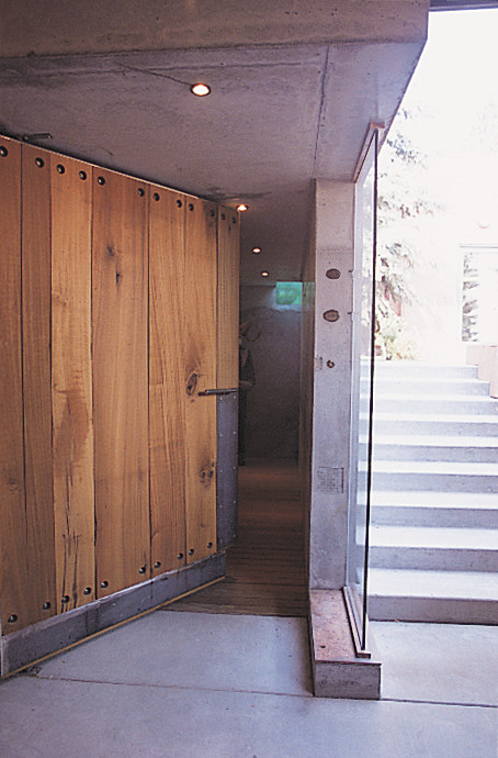 Imagen de distribuidor contemporáneo de tamaño medio con paredes grises, suelo de cemento y puerta de madera en tonos medios