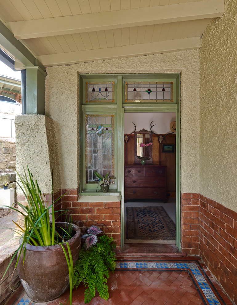 Ejemplo de entrada clásica con suelo de baldosas de terracota, puerta simple y puerta verde