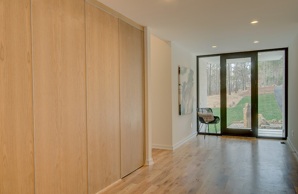 Inspiration pour une porte d'entrée minimaliste de taille moyenne avec un mur blanc, parquet clair, une porte simple et une porte marron.