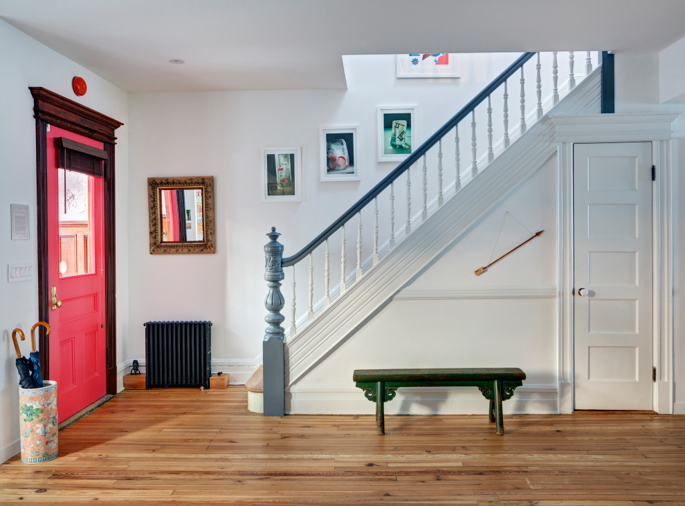 Idées déco pour un hall d'entrée éclectique avec un mur blanc, un sol en bois brun, une porte simple et une porte rouge.