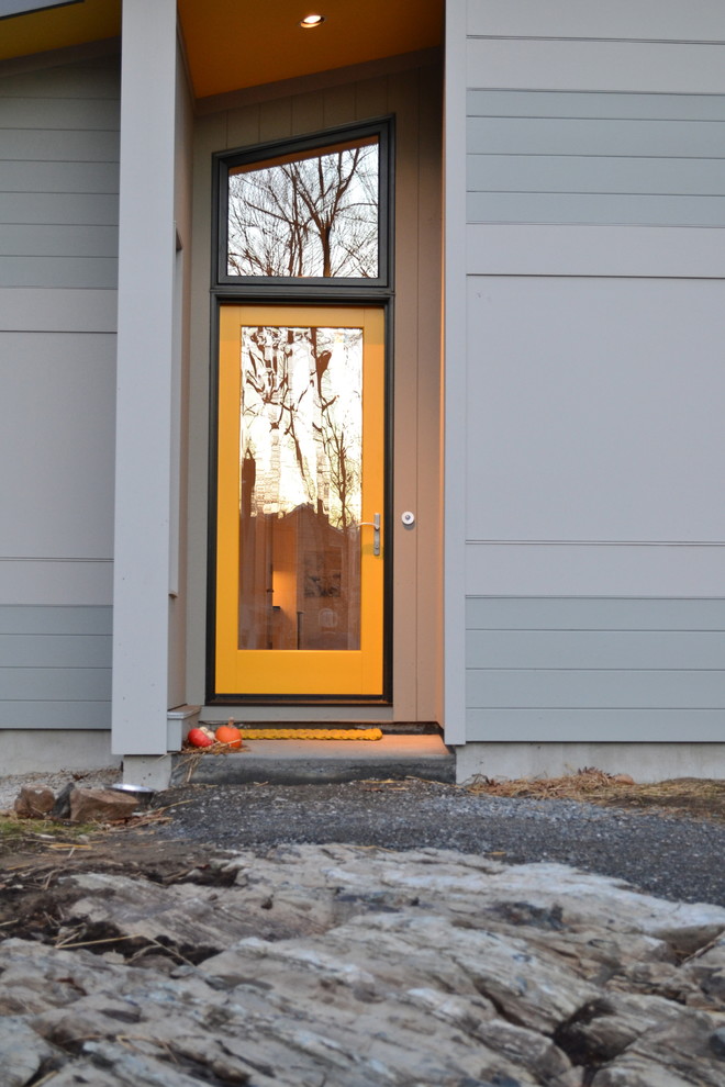 На фото: маленькая входная дверь в современном стиле с одностворчатой входной дверью, стеклянной входной дверью, бежевыми стенами и бетонным полом для на участке и в саду с